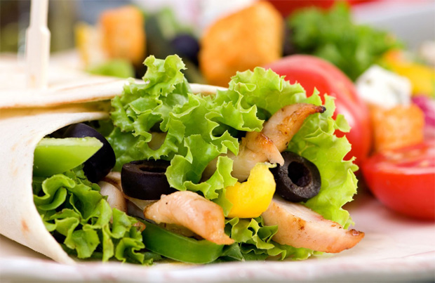 В лаваше салат, рыба и маслины на фоне свежих овощей