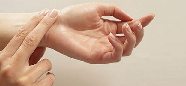 Женщина сама себе измеряет пульс на запястье левой руки