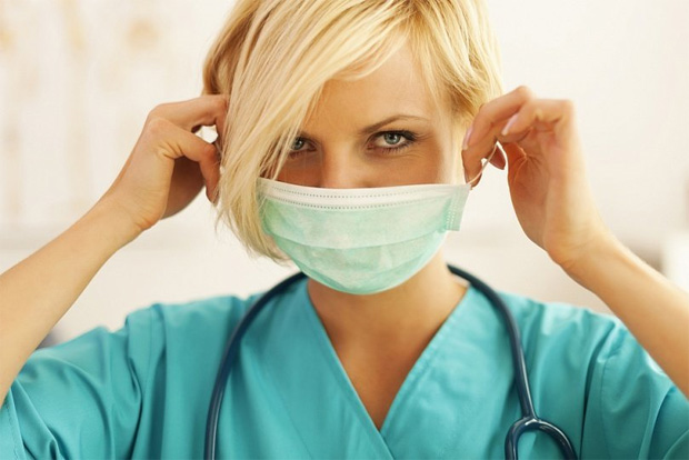 Красивая медсестра блондинка одевает защитную маску