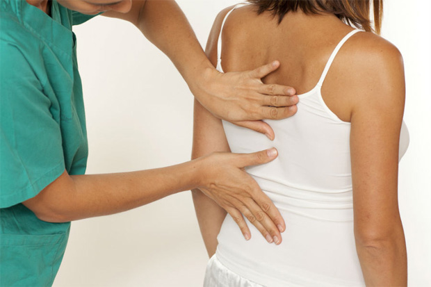 Врач выполняет давление на спину пациентки с болями в теле
