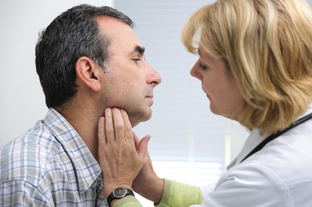 врач обследует горло мужчине