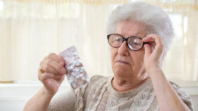 пожилая женщина смотрит на таблетки